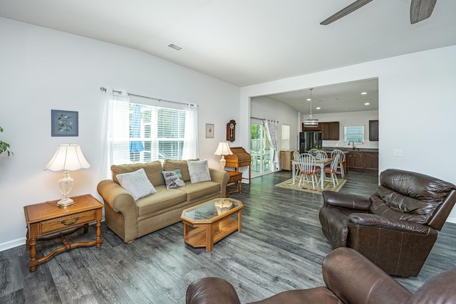 living area featuring ceiling fan, baseboards, vaulted ceiling, dark wood-type flooring, and visible vents