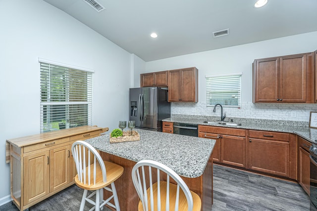 kitchen with a sink, dishwasher, dark wood finished floors, refrigerator with ice dispenser, and visible vents