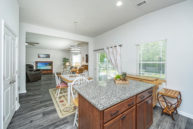 kitchen featuring ceiling fan, visible vents, hanging light fixtures, dark wood finished floors, and open floor plan