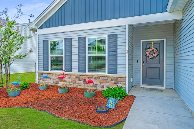 property entrance with board and batten siding and stone siding