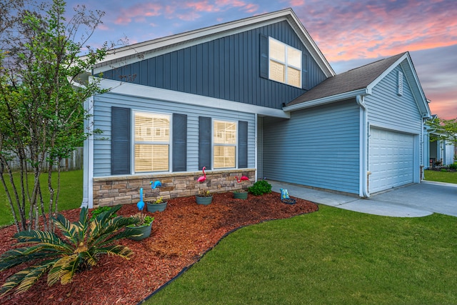 view of front of home with board and batten siding, driveway, a front yard, a garage, and stone siding