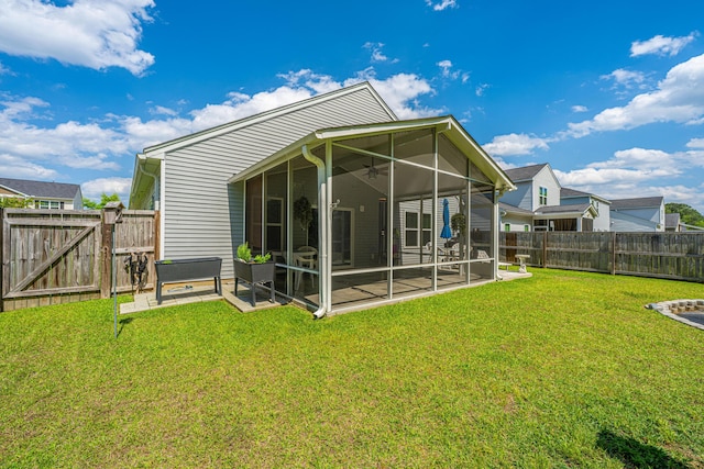 rear view of house with a lawn, a gate, a fenced backyard, and a sunroom