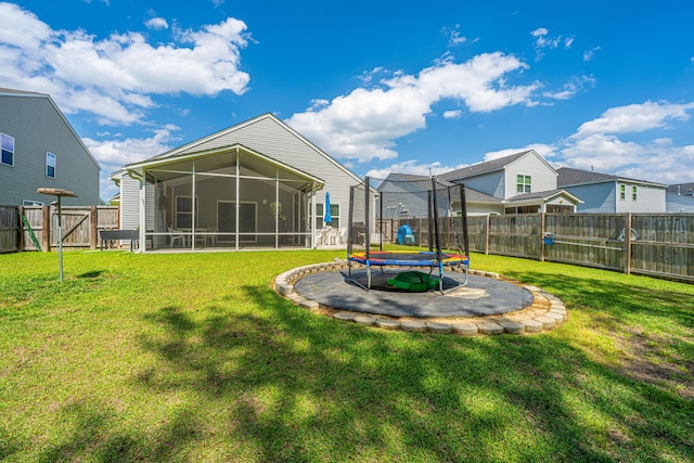 back of property featuring a sunroom, a trampoline, and a lawn