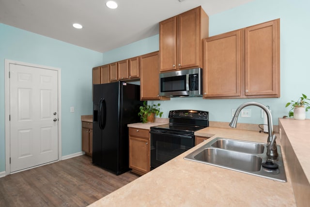 kitchen featuring recessed lighting, light countertops, wood finished floors, a sink, and black appliances
