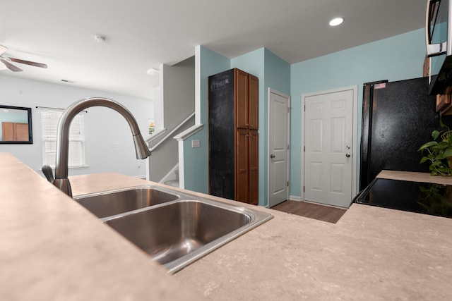 kitchen featuring light countertops, wood finished floors, a ceiling fan, a sink, and freestanding refrigerator