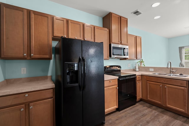 kitchen featuring a sink, visible vents, recessed lighting, wood finished floors, and black appliances