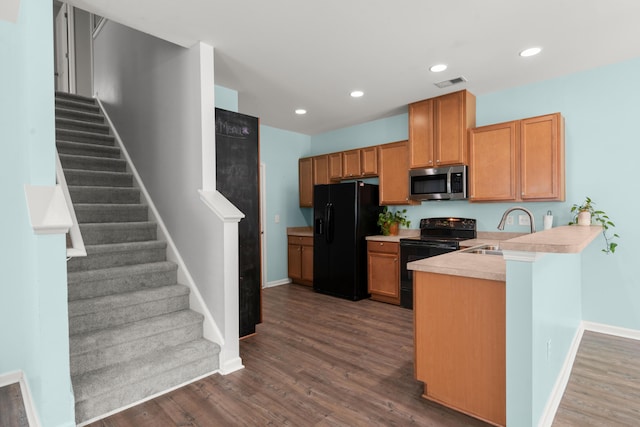 kitchen featuring a sink, black appliances, visible vents, light countertops, and dark wood-style floors