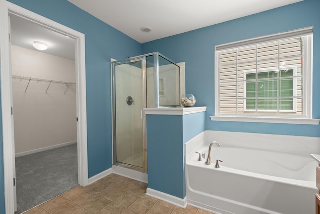 full bath featuring a bath, a spacious closet, a shower stall, and tile patterned flooring