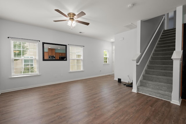 unfurnished living room with baseboards, a ceiling fan, stairs, and dark wood-style flooring