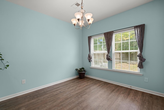 spare room featuring an inviting chandelier, dark wood-type flooring, and baseboards