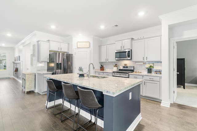 kitchen with a kitchen breakfast bar, backsplash, stainless steel appliances, sink, and a center island with sink