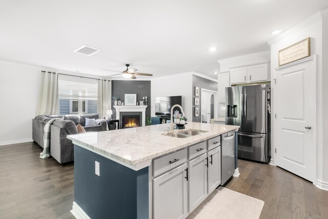 kitchen featuring ceiling fan, sink, light stone counters, a kitchen island with sink, and appliances with stainless steel finishes