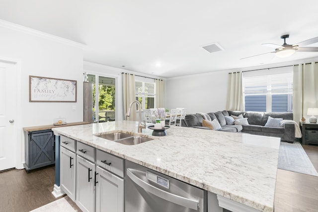 kitchen with stainless steel dishwasher, ornamental molding, ceiling fan, sink, and a center island with sink