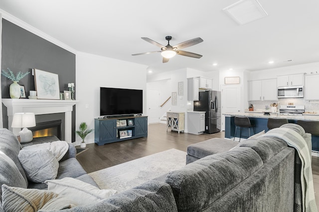 living room featuring crown molding, ceiling fan, and dark wood-type flooring