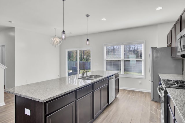 kitchen featuring decorative light fixtures, sink, dark brown cabinetry, a kitchen island with sink, and stainless steel appliances