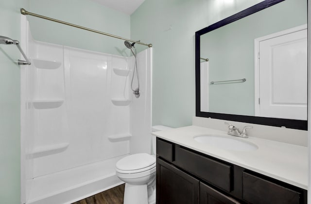 bathroom featuring hardwood / wood-style flooring, toilet, walk in shower, and vanity