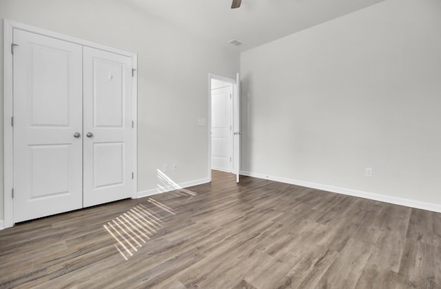 unfurnished bedroom with ceiling fan, a closet, and hardwood / wood-style floors