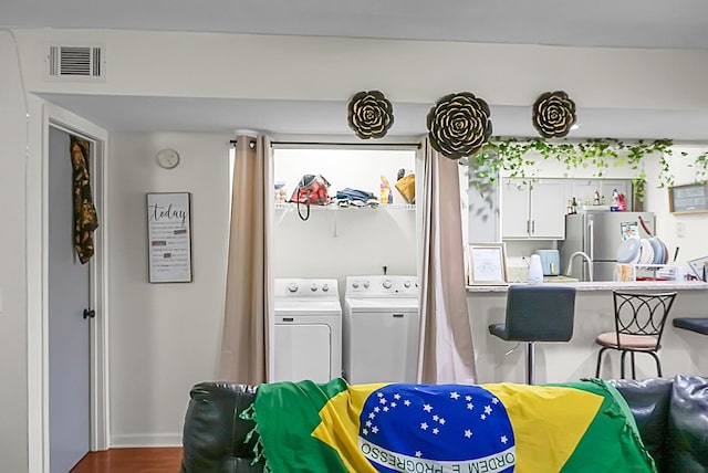 washroom featuring visible vents, independent washer and dryer, wood finished floors, and laundry area