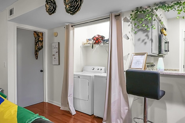 laundry area featuring washing machine and clothes dryer, laundry area, visible vents, and wood finished floors