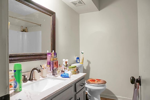 bathroom featuring vanity, toilet, a shower, and visible vents