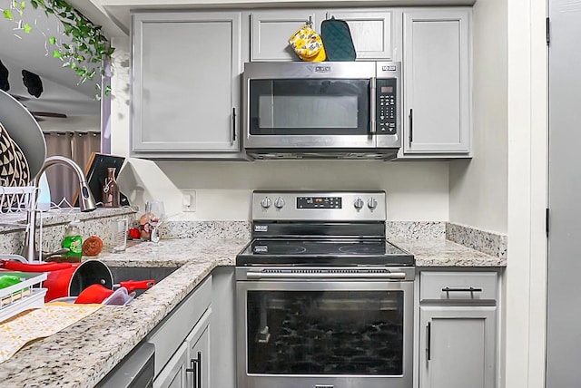 kitchen featuring a sink, light stone countertops, and stainless steel appliances