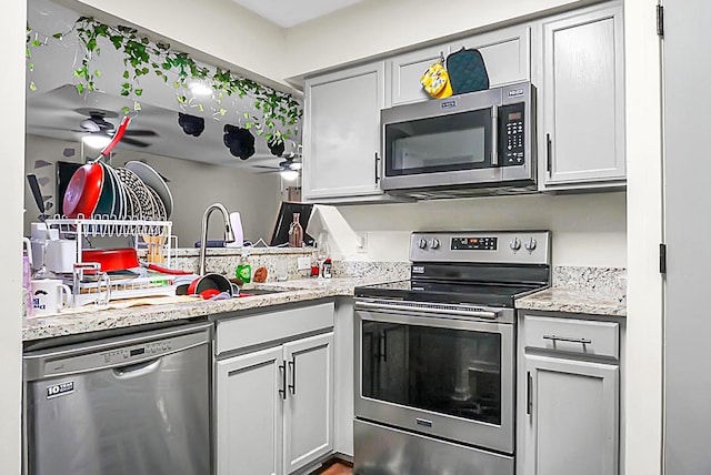 kitchen with light stone countertops, stainless steel appliances, and a sink