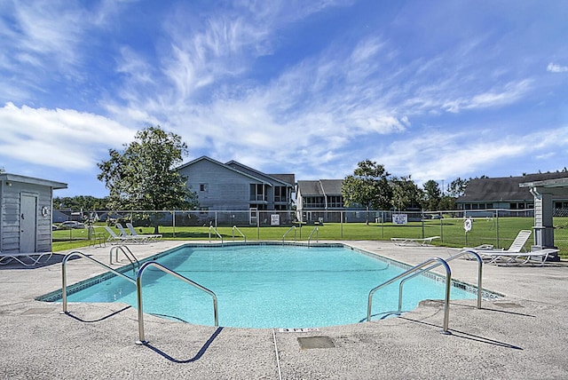 pool with a patio area, a lawn, and fence