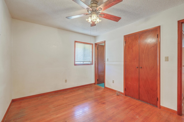 unfurnished bedroom with a closet, a textured ceiling, light wood-type flooring, and baseboards