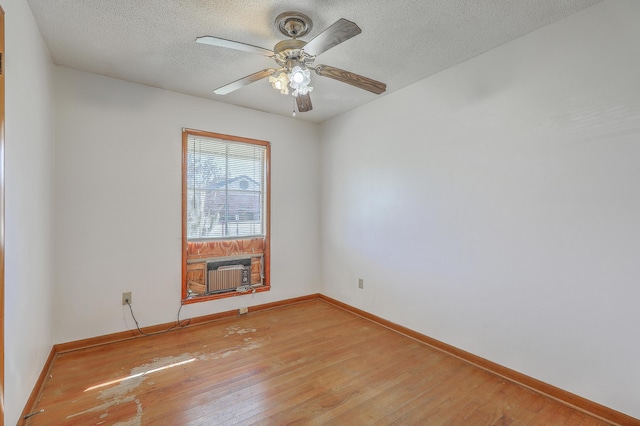 unfurnished room with ceiling fan, baseboards, light wood-type flooring, cooling unit, and a textured ceiling