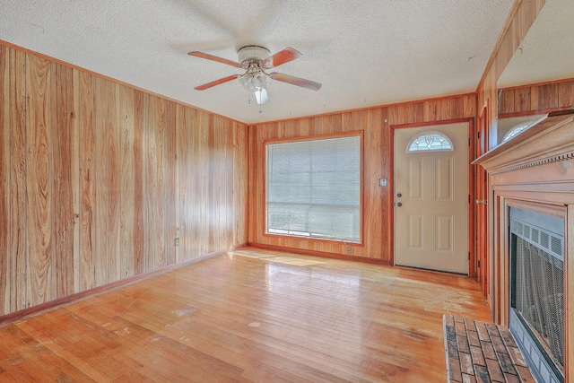 foyer with hardwood / wood-style floors, a fireplace with flush hearth, plenty of natural light, and wood walls