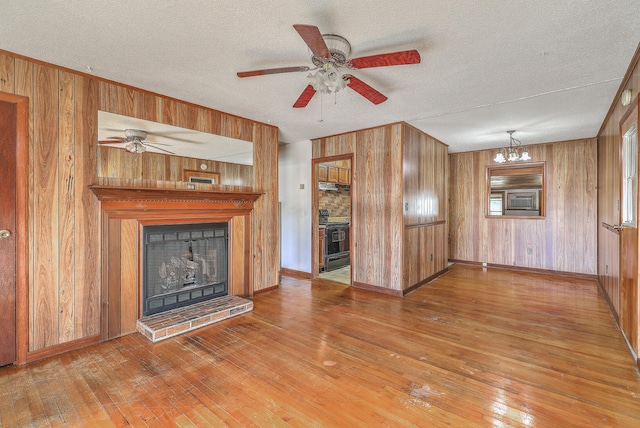 unfurnished living room featuring a fireplace with raised hearth, wood walls, and hardwood / wood-style flooring