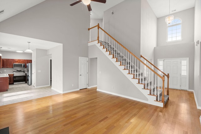 living room with sink, high vaulted ceiling, ceiling fan with notable chandelier, and light wood-type flooring