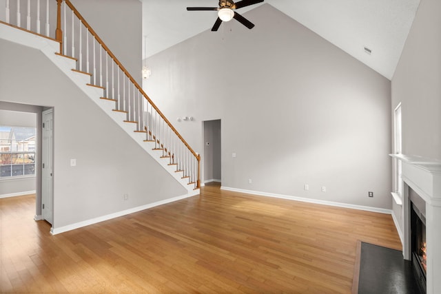 unfurnished living room featuring hardwood / wood-style floors, ceiling fan, and high vaulted ceiling