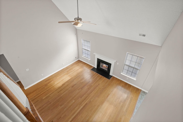 unfurnished living room featuring ceiling fan, high vaulted ceiling, and hardwood / wood-style flooring