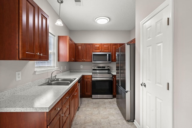 kitchen with a textured ceiling, decorative light fixtures, sink, and appliances with stainless steel finishes