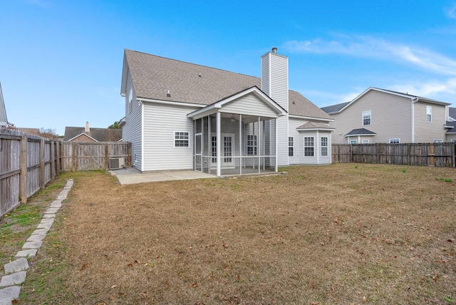 rear view of house with a sunroom, a patio area, and a lawn