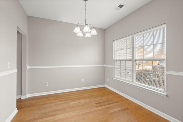 spare room featuring light hardwood / wood-style floors and an inviting chandelier