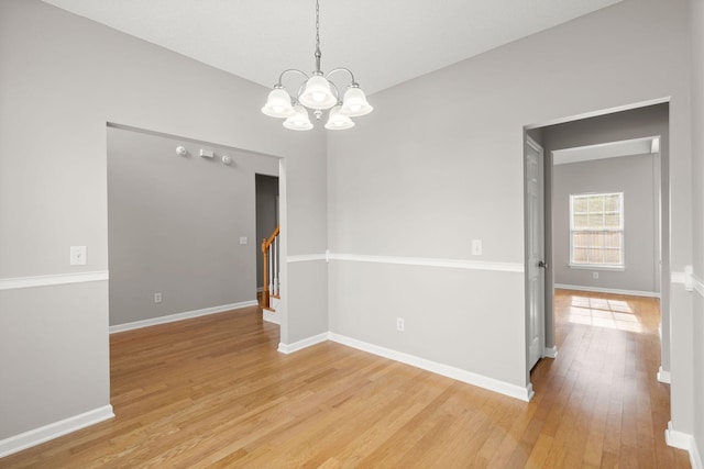 spare room with a notable chandelier and light hardwood / wood-style floors