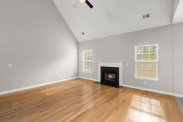 unfurnished living room featuring high vaulted ceiling, ceiling fan, light wood-type flooring, and a wealth of natural light