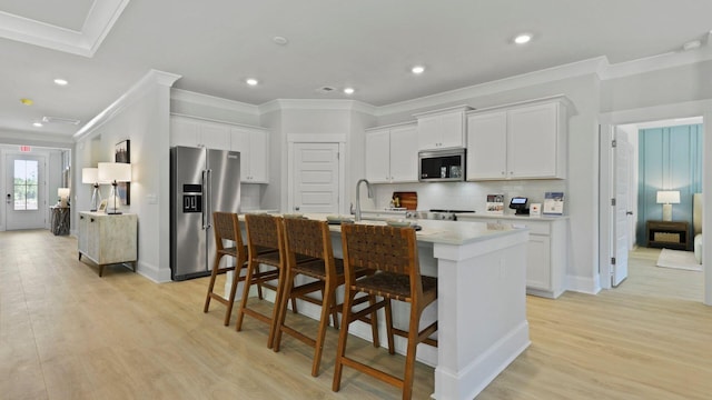 212 Bilge Rd, Ridgeville, SC 29472 - kitchen with appliances with stainless steel finishes, ornamental molding, a kitchen island with sink, backsplash, and a breakfast bar area