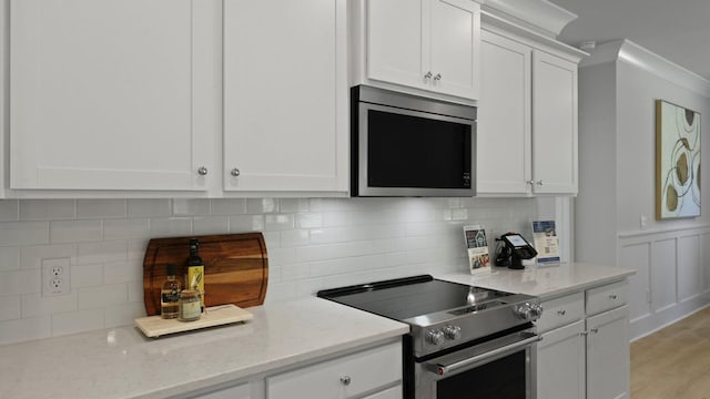 212 Bilge Rd, Ridgeville, SC 29472 - kitchen with stainless steel appliances, white cabinetry, light stone countertops, decorative backsplash, and light wood-type flooring