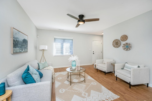 living room featuring baseboards, a ceiling fan, and wood finished floors