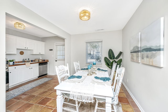 tiled dining area featuring visible vents, baseboards, and a sink