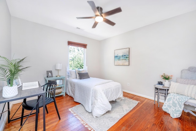 bedroom featuring baseboards, visible vents, ceiling fan, and wood finished floors