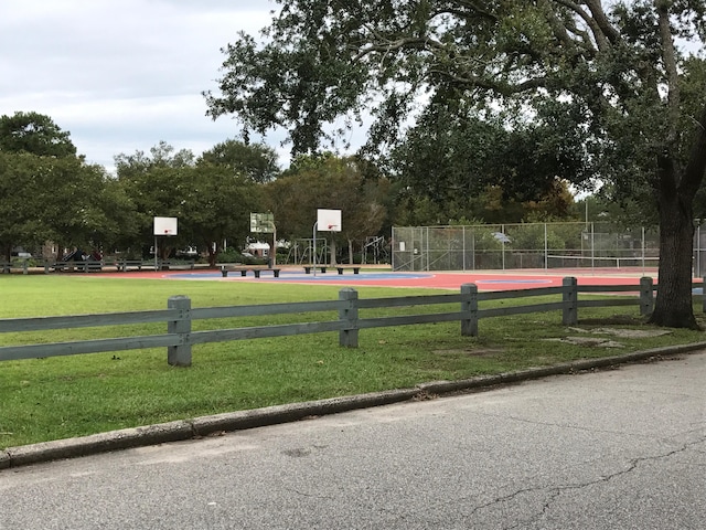 view of property's community featuring community basketball court, a yard, and fence