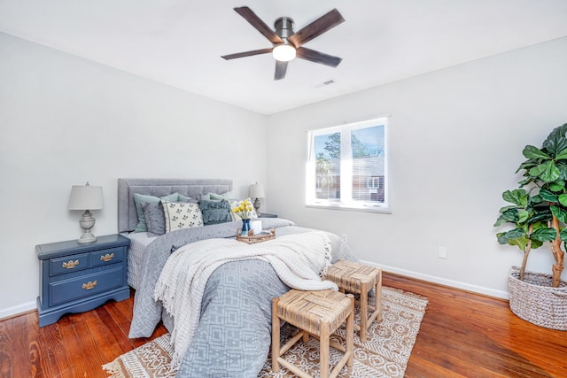 bedroom with a ceiling fan, wood finished floors, visible vents, and baseboards