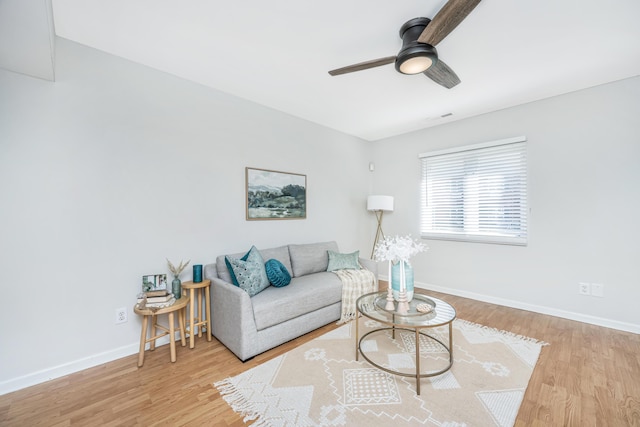 living area with a ceiling fan, visible vents, baseboards, and wood finished floors