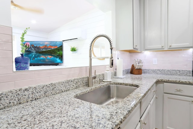 room details featuring a wall unit AC, tasteful backsplash, light stone counters, and a sink