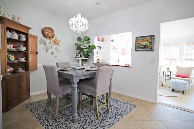 dining area featuring baseboards, a chandelier, and light tile patterned flooring