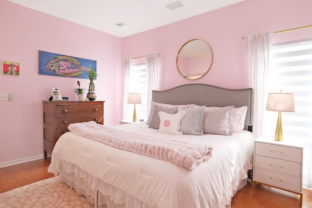 bedroom with visible vents, baseboards, and wood finished floors